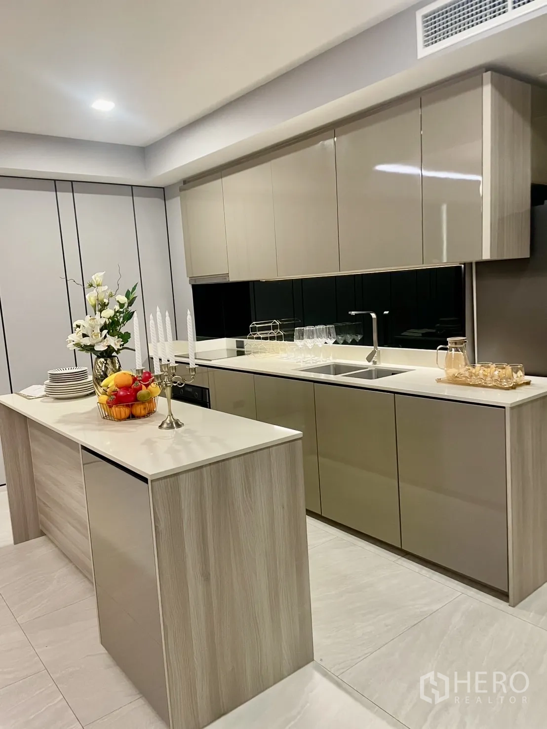 公寓 出租在Watthana, Bangkok - 现代厨房中岛，亮面柜门与橱柜下灯带。