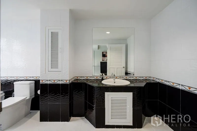 Townhouse for sale - Black and white bathroom with large mirror, corner vanity and toilet.