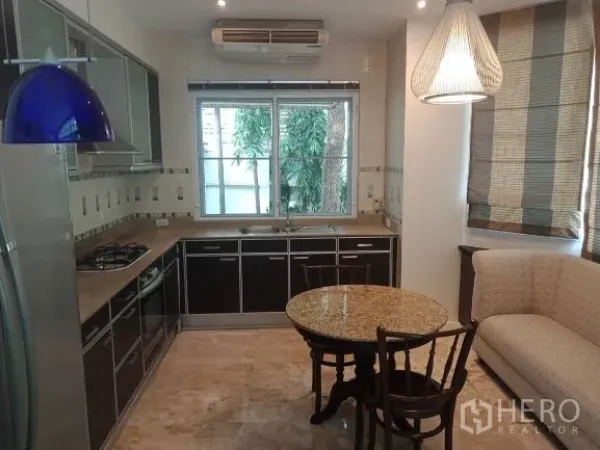 Detached House for rent in Bang Rak, Bangkok - Fitted kitchen with dark cabinetry, gas cooktop, window and a cozy breakfast nook.