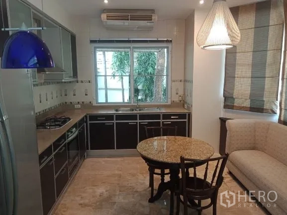 Detached House for rent in Bang Rak, Bangkok - Fitted kitchen with dark cabinetry, gas cooktop, window and a cozy breakfast nook.
