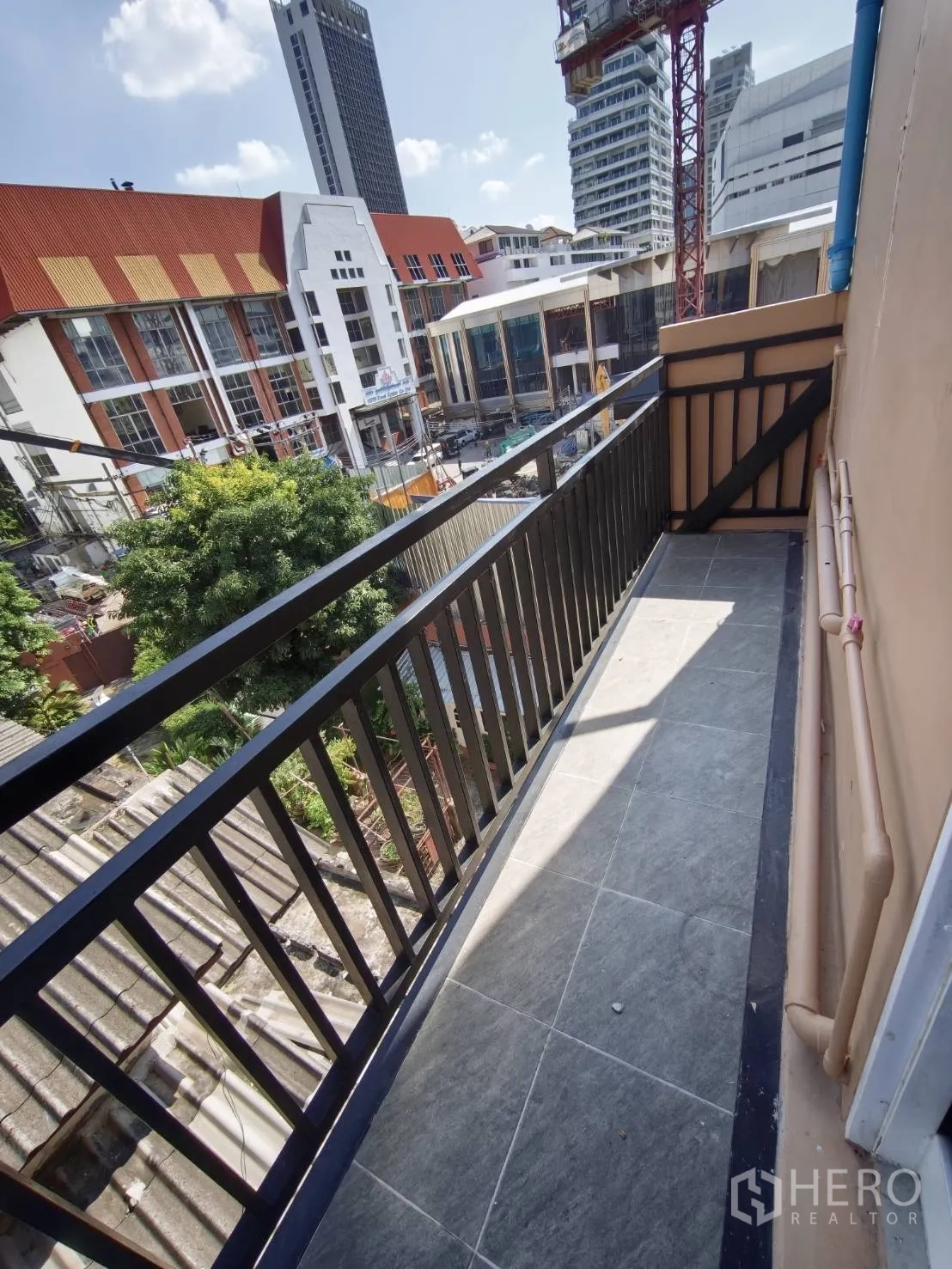 零售空间 for rent in Watthana, Bangkok - 狭长阳台俯瞰屋顶与城市景观及施工吊塔。