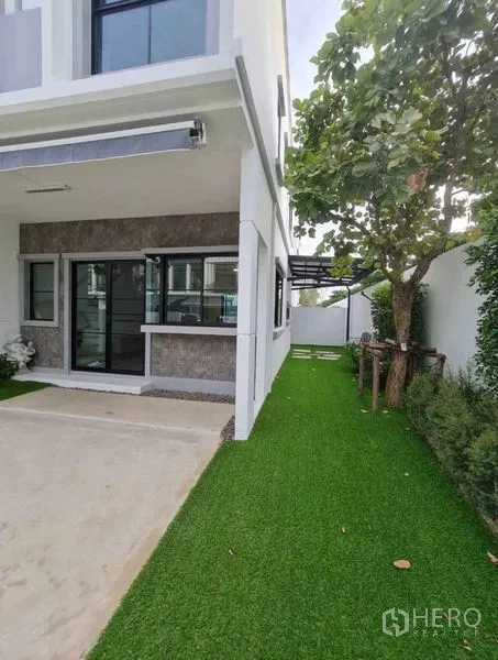 Townhouse for rent in Bang Phli, Samut Prakan - Townhouse side exterior with lawn, mature tree and covered walkway.