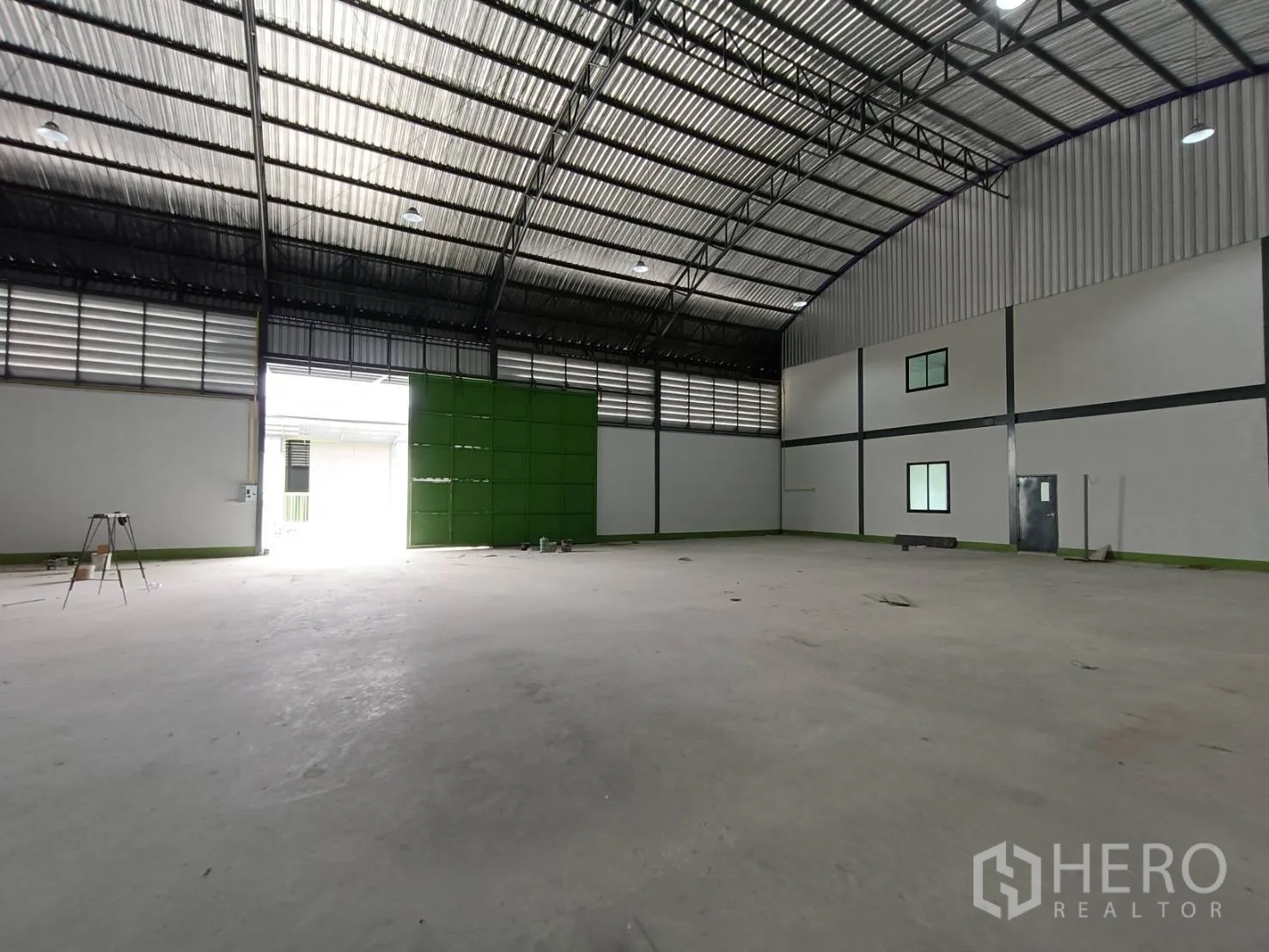 工厂 出租在Lam Luk Ka, Pathum Thani - 仓库视角朝绿色装卸门，拱形屋顶与通风板清晰可见。