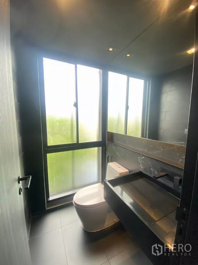 Townhouse for rent in Huai Khwang, Bangkok - Powder room with frosted floor-to-ceiling windows, black vanity and toilet.