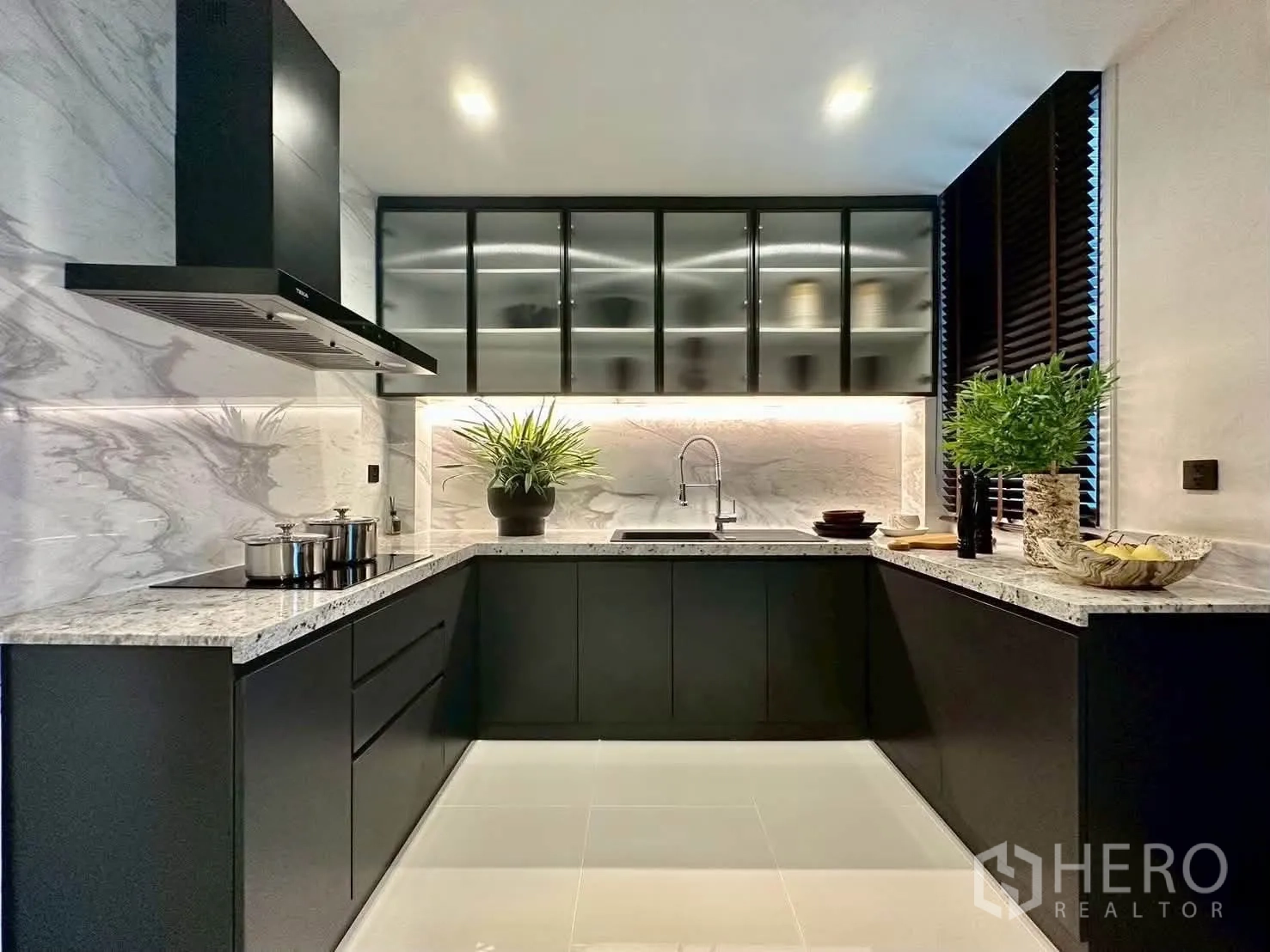 独栋房屋 for rent or sale in Suan Luang, Bangkok - U 型现代厨房，深色橱柜、大理石纹防溅板与橱柜下照明。