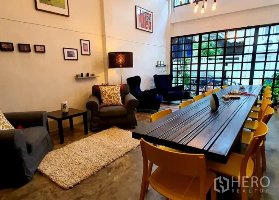 ทาวน์เฮาส์ ให้เช่าในKhlong Toei, Bangkok - ห้องนั่งเล่นและรับประทานอาหารสไตล์ลอฟต์ โต๊ะยาว เก้าอี้สีเหลือง เก้าอี้อาร์มเชียร์ และผนังกระจกกรอบดำ
