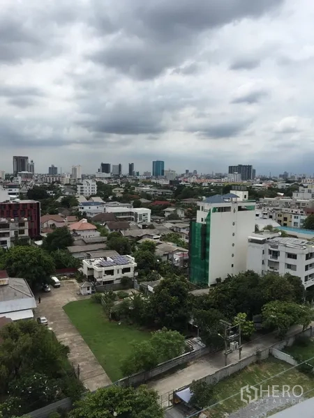 Condominium for rent in Watthana, Bangkok - High-floor city view over Ekkamai with mid-rise buildings and green spaces under a cloudy sky.