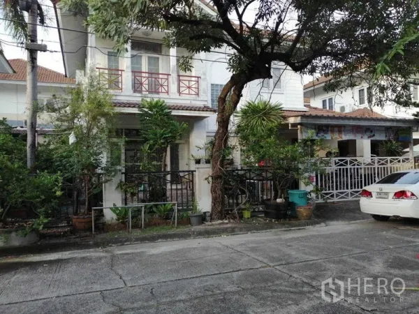 独立式住宅 出售在Prawet, Bangkok - 街景：带阳台的两层独栋住宅，树木与前院。