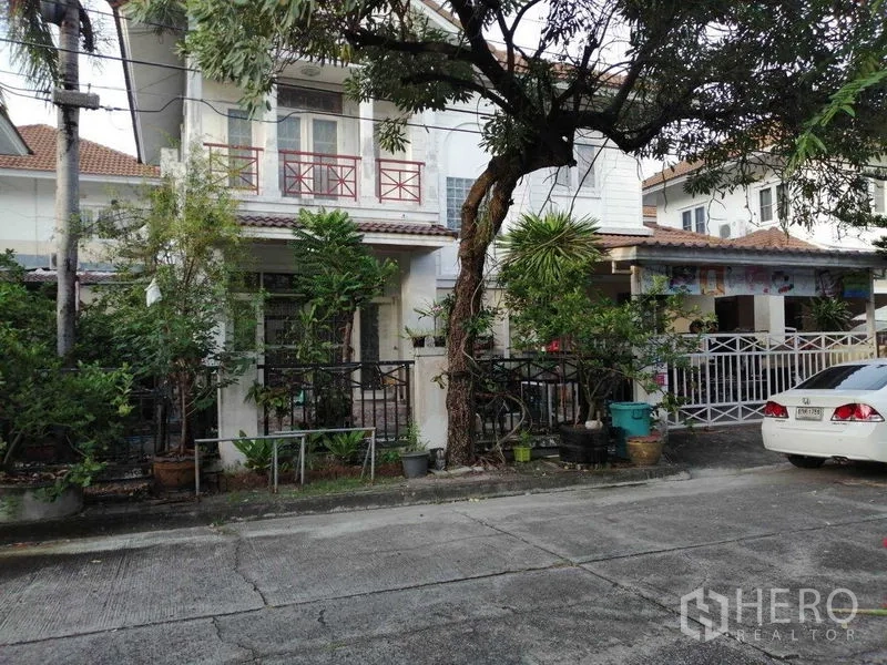 独立式住宅 出售在Prawet, Bangkok - 街景：带阳台的两层独栋住宅，树木与前院。