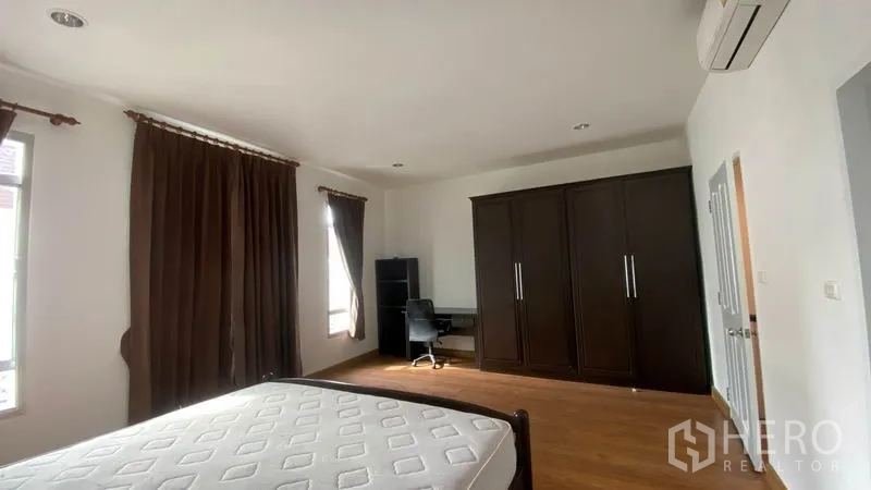 联排别墅 出租在Wang Thonglang, Bangkok - 温馨次卧，单人床、衣柜、斗柜与木地板。