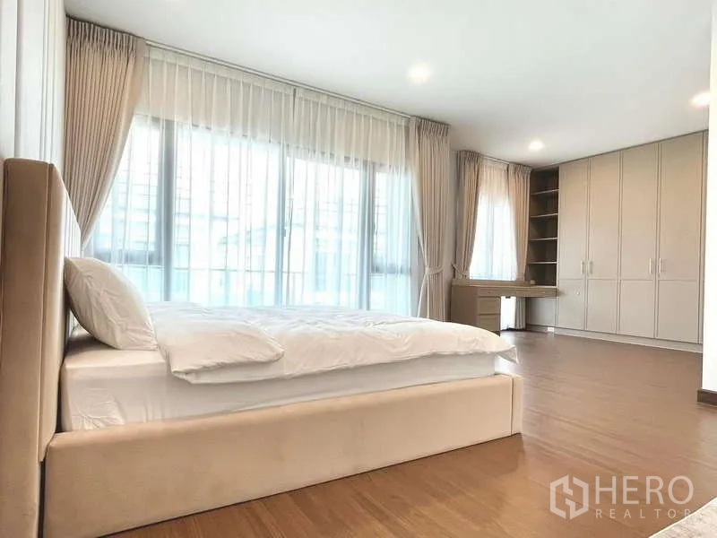 Detached House for rent in Bang Phli, Samut Prakan - Large bedroom with full-height windows, built-in wardrobes and a work desk.