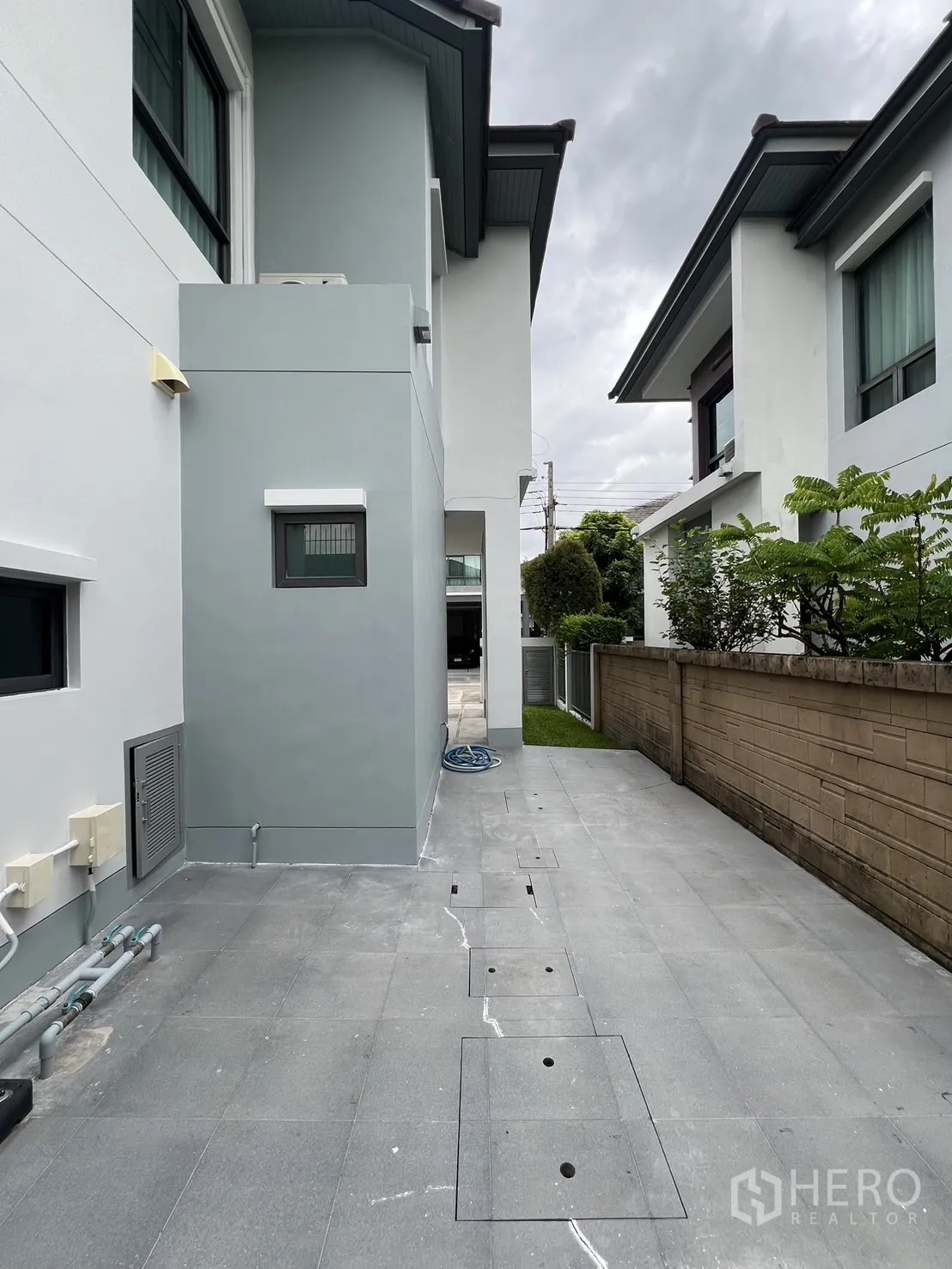 Detached House for rent in Bang Kapi, Bangkok - Side service yard with tiled walkway and exposed utility lines.