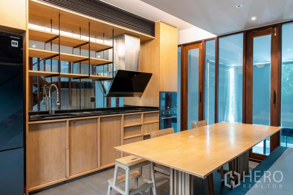 Townhouse for rent in Lat Phrao, Bangkok - Open kitchen and dining area with built-in shelves and pool view.