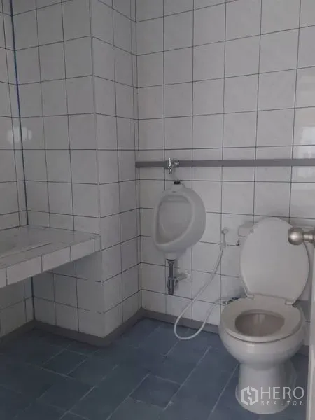 办公空间 出租在Pathum Wan, Bangkok - 办公楼卫生间，瓷砖墙地，配洗手台、小便池与坐便器