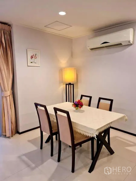 Apartment for rent - Four-seat dining area with table, padded chairs and warm floor lamp lighting.