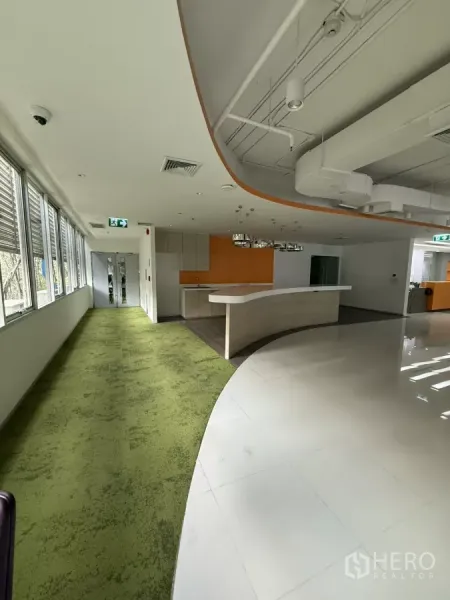 Retail Space for rent in Bang Rak, Bangkok - Curved reception counter, green carpet walkway and kitchenette in a modern retail space.