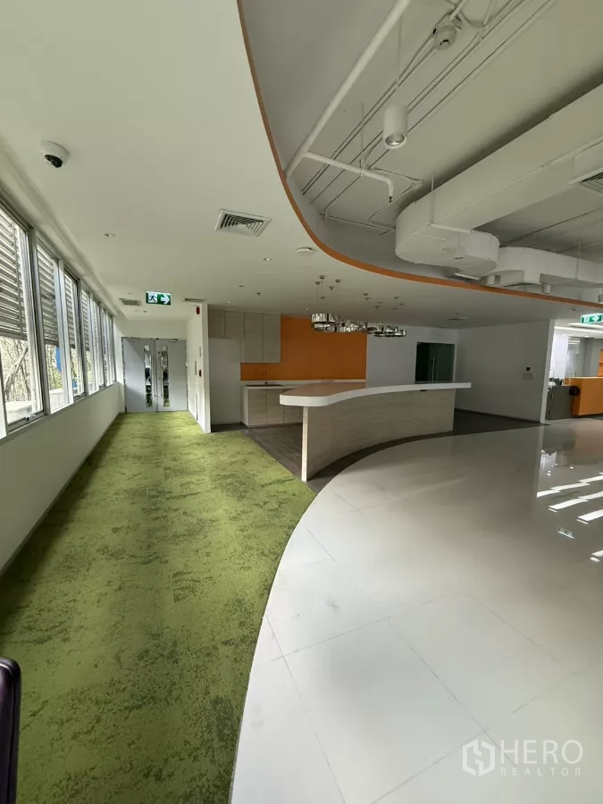 Retail Space for rent in Bang Rak, Bangkok - Curved reception counter, green carpet walkway and kitchenette in a modern retail space.