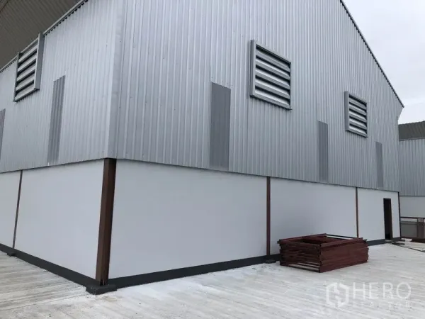 Factory for rent or sale in Sai Noi, Nonthaburi - Side elevation of a steel-clad warehouse with louver vents and a spacious concrete yard.