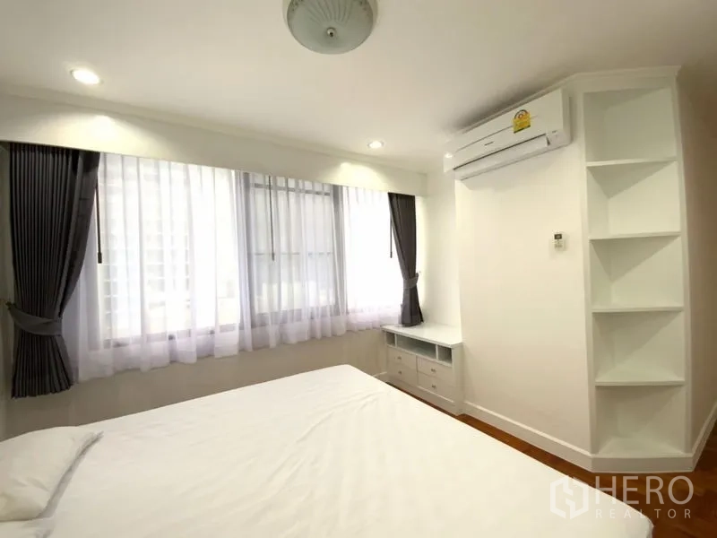 公寓 出租在Watthana, Bangkok - 卧室一角配大窗、壁挂空调、开放式层架与矮柜。