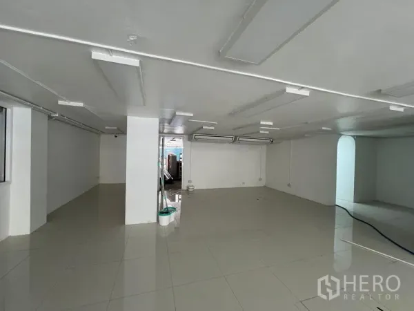 Retail Space for rent in Khlong Toei, Bangkok - Open-plan white retail interior with glossy tiled floors and ceiling panel lights.