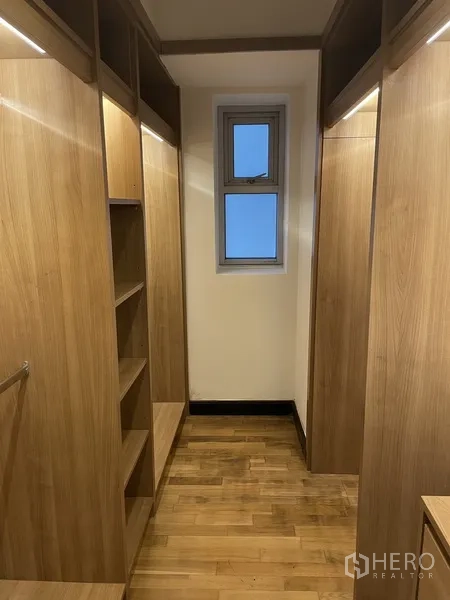 公寓 出租或出售在Pathum Wan, Bangkok - 步入式衣帽间，内置木质柜体与悬挂空间，配小窗采光。