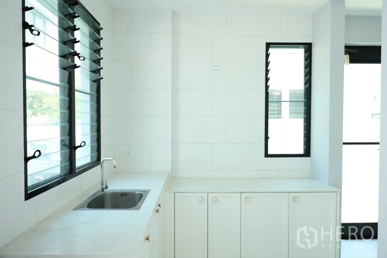 Detached House for rent or sale in Saphan Sung, Bangkok - Separate Thai kitchen with white cabinetry, sink, and louvered windows.