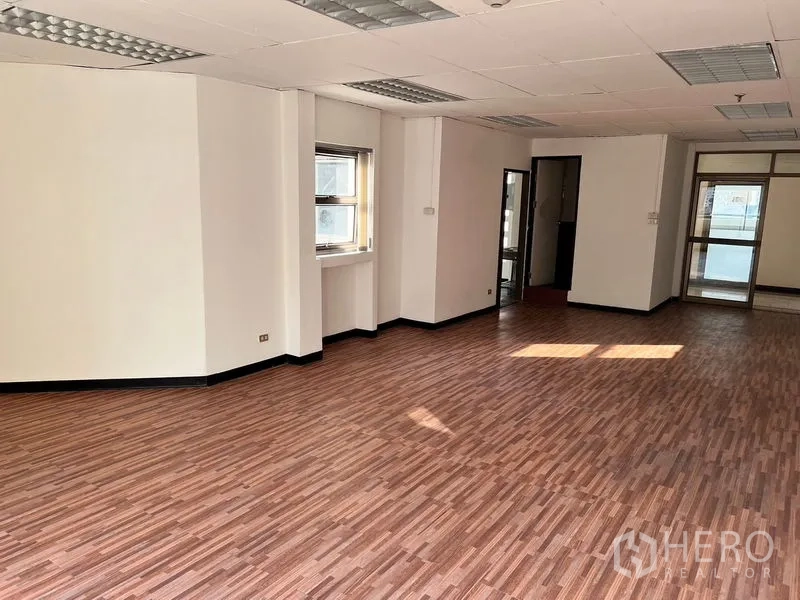 办公空间 出租在Pathum Wan, Bangkok - 办公角落带窗与吊顶灯，旁有通往内部配套的门。