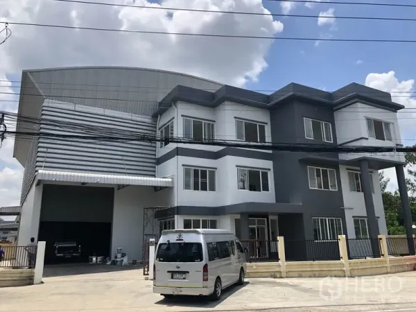 คลังสินค้า ให้เช่าหรือขายในLam Luk Ka, Pathum Thani - ด้านหน้าตึกสำนักงานเชื่อมกับโกดัง พร้อมประตูม้วนขนาดใหญ่ทางเข้า