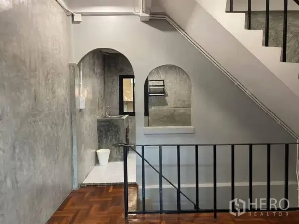 带办公室的家 出租在Bang Rak, Bangkok - 楼梯间，黑色金属栏杆、拱形墙洞与亮面拼花木地板。