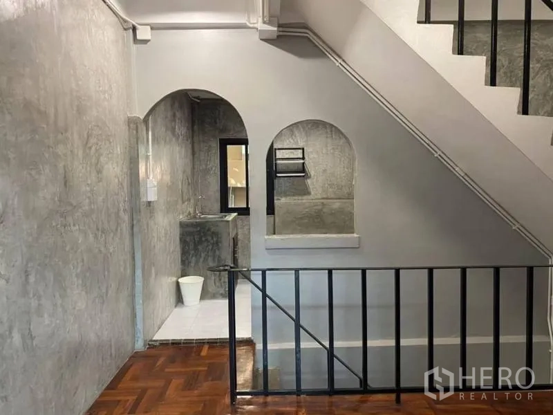 带办公室的家 出租在Bang Rak, Bangkok - 楼梯间，黑色金属栏杆、拱形墙洞与亮面拼花木地板。