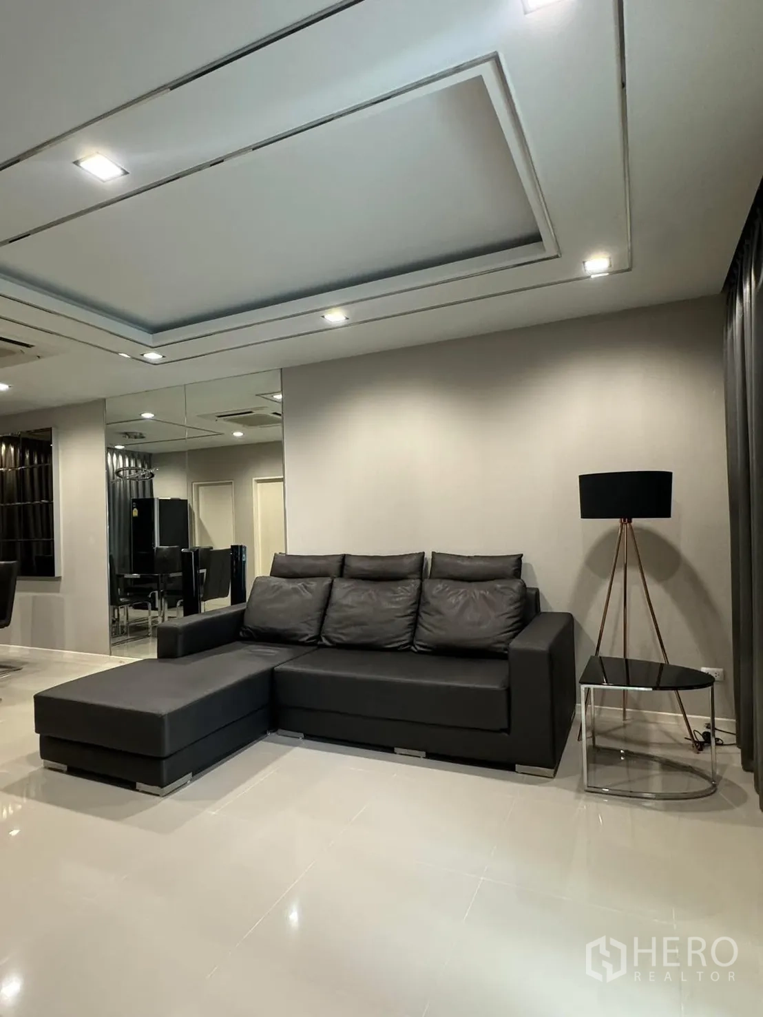 Townhouse for rent in Suan Luang, Bangkok - Cozy lounge corner with black sectional sofa, side table and floor lamp.