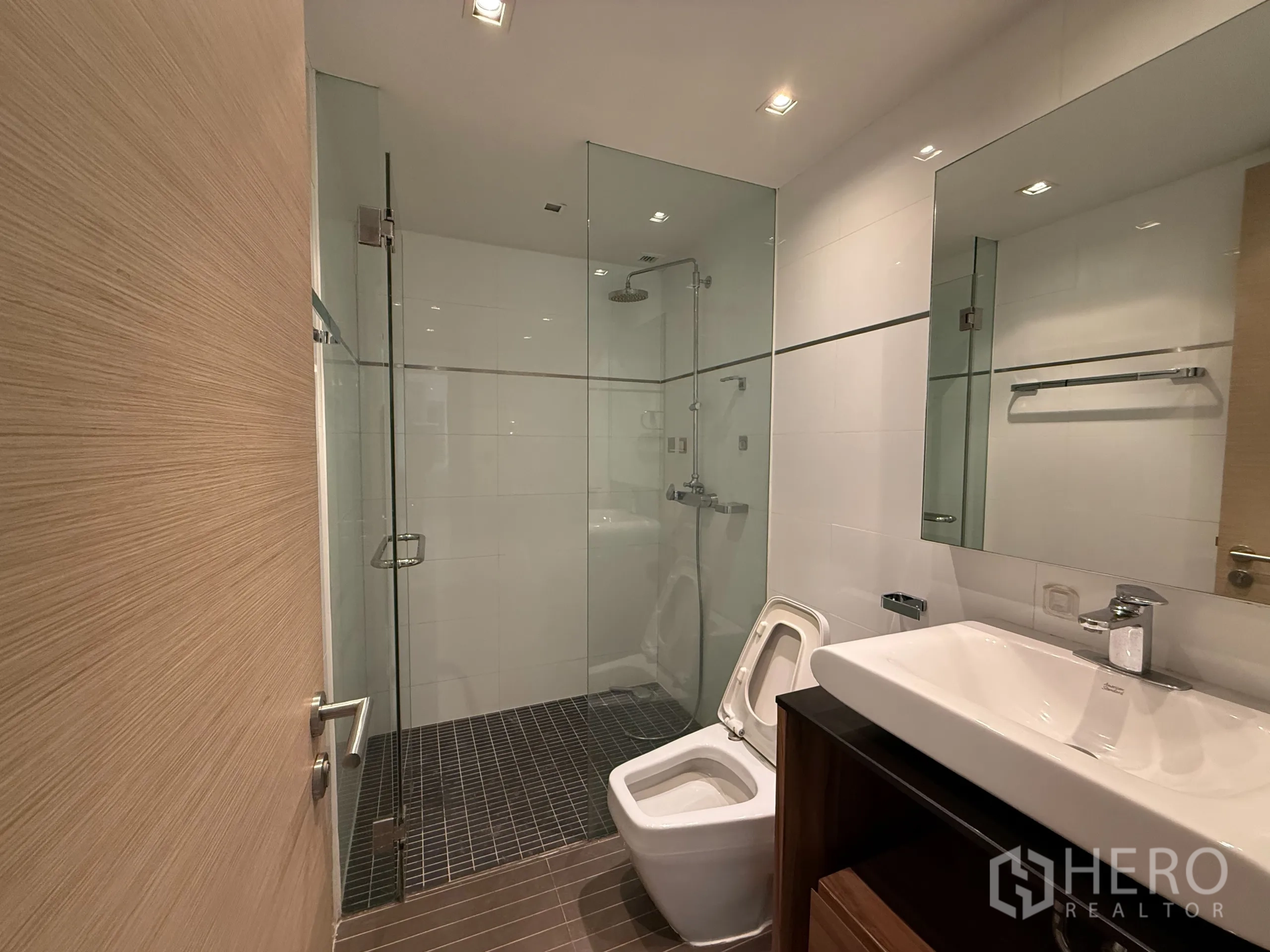 Condominium for rent in Phaya Thai, Bangkok - Bathroom with glass‑enclosed shower, white tiles and vanity with basin.