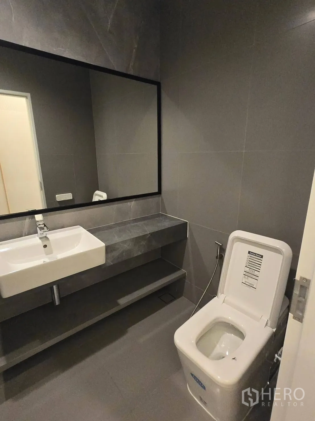 บ้าน for rent or sale in Bang Phli, Samut Prakan - ห้องน้ำแขกพร้อมเคาน์เตอร์ยาว กระจกบานใหญ่ และโถสุขภัณฑ์สีขาว