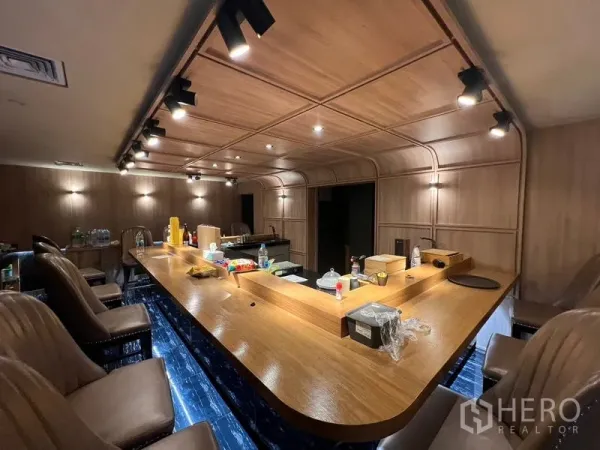 Retail Space for rent in Bang Rak, Bangkok - Warm wood bar counter with track lighting and upholstered stools.