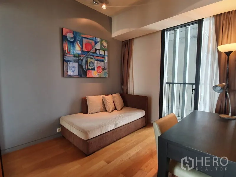 Condominium for rent in Sathon, Bangkok - Study or guest nook with daybed, work desk and door to a small balcony.