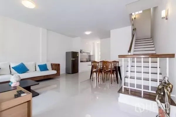 联排别墅 出租在Watthana, Bangkok - 宽敞客厅，沙发与餐桌，楼梯通往楼上