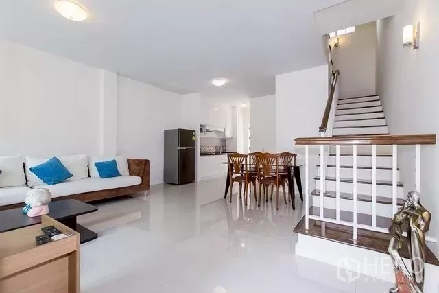 联排别墅 出租在Watthana, Bangkok - 宽敞客厅，沙发与餐桌，楼梯通往楼上
