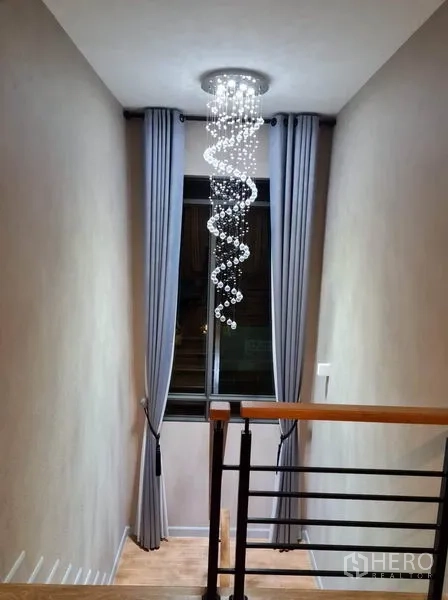 Detached House for rent or sale in Saphan Sung, Bangkok - Stairwell with spiral crystal chandelier and floor-to-ceiling curtains.