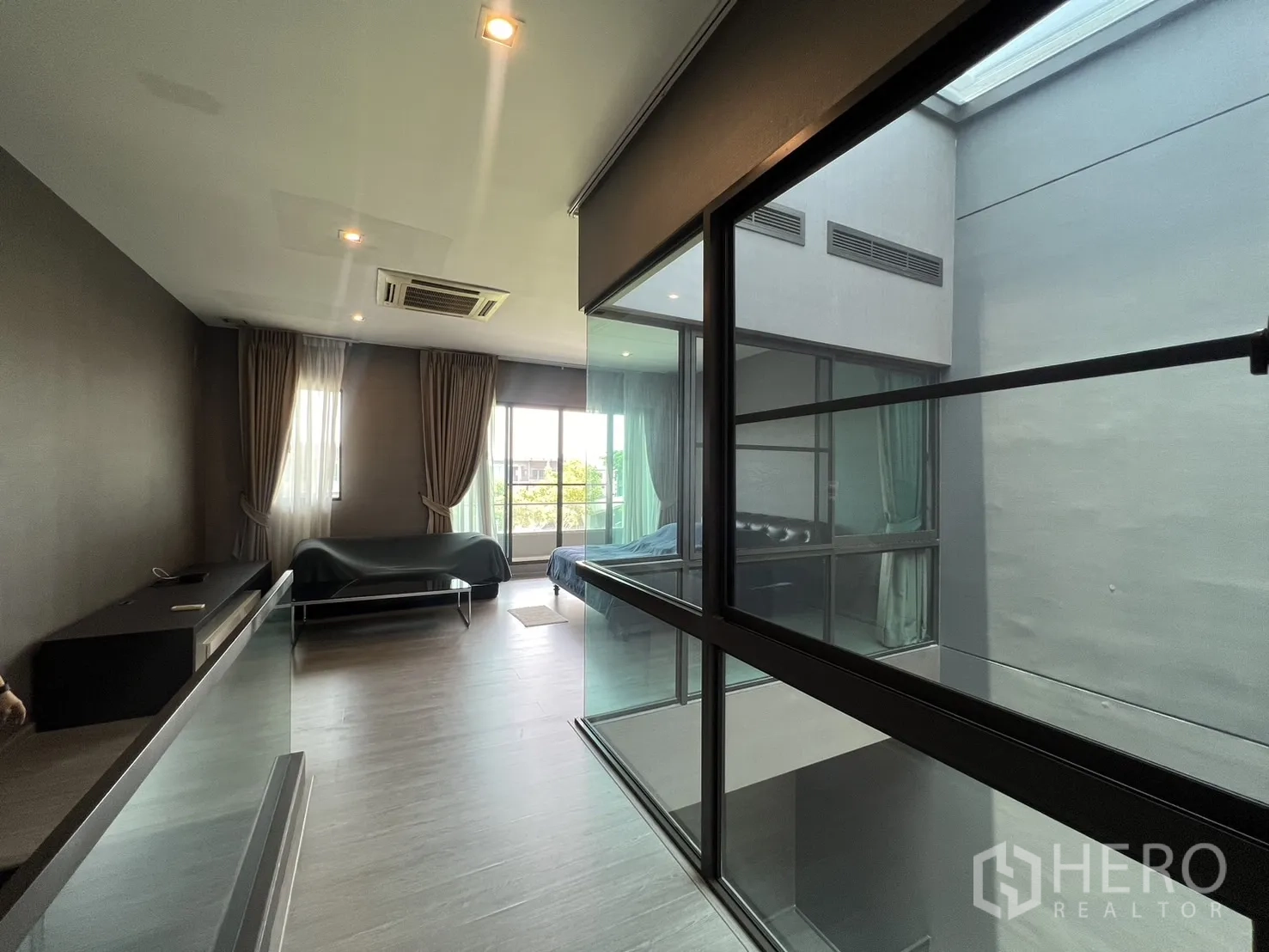 Townhouse for rent in Lat Phrao, Bangkok - Spacious upper living or bedroom with balcony access and atrium glazing.