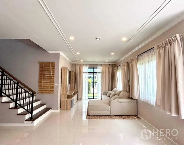独立式住宅 出租在Khlong Sam Wa, Bangkok - 开放式起居空间，带楼梯、沙发与落地窗帘