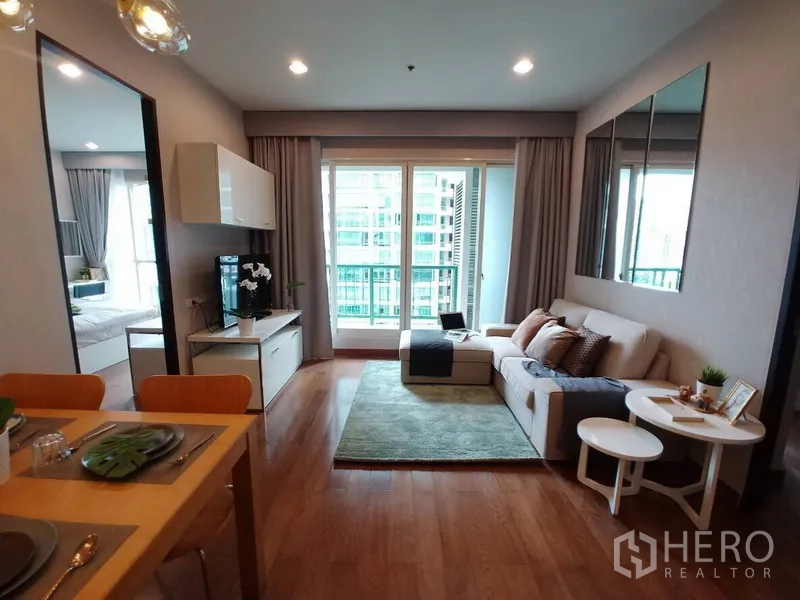 公寓 出租在Pathum Wan, Bangkok - 采光明亮的客厅，木地板，沙发与电视柜，落地阳台门可观城市景色。