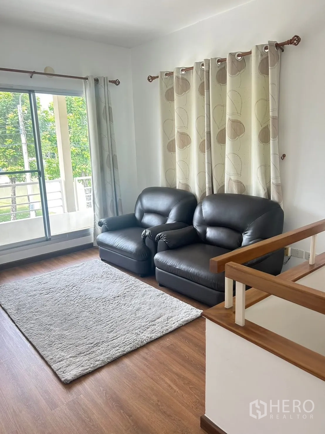 Detached House for rent in Bang Na, Bangkok - Upstairs lounge area with two leather sofas, rug, and balcony sliding door.