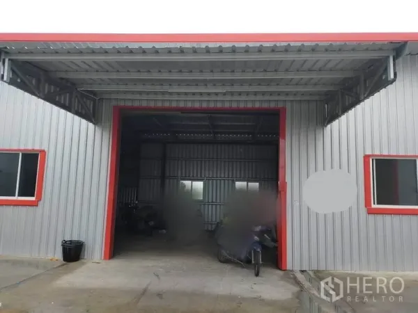 Warehouse for rent in Bang Yai, Nonthaburi - Metal-clad warehouse facade with wide covered loading bay, red trim and windows.