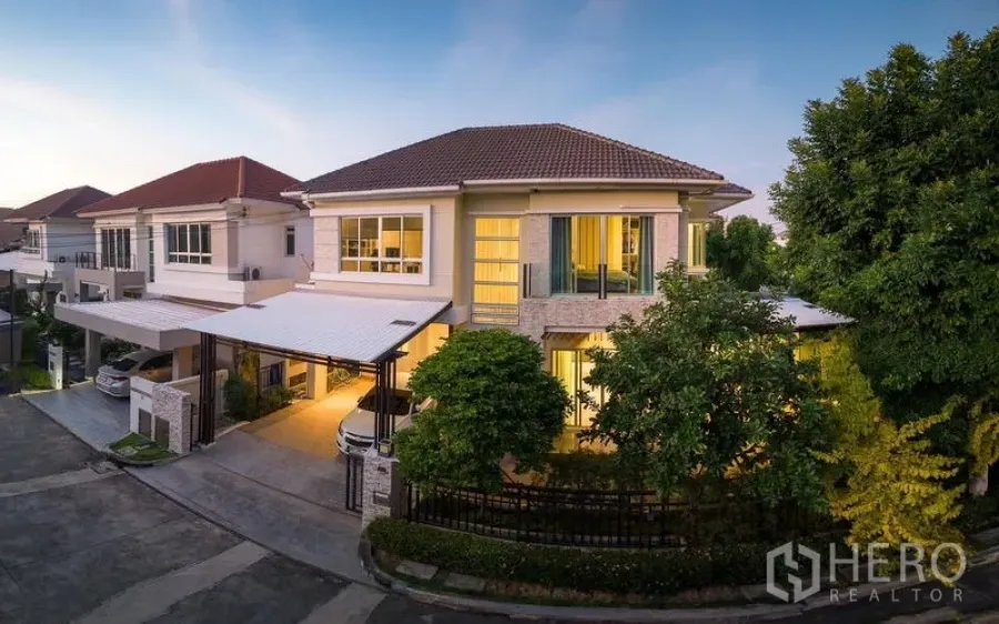 Detached House for rent or sale in Saphan Sung, Bangkok - Modern two‑storey detached house on a corner plot with double carport and warm exterior lighting in a quiet community.