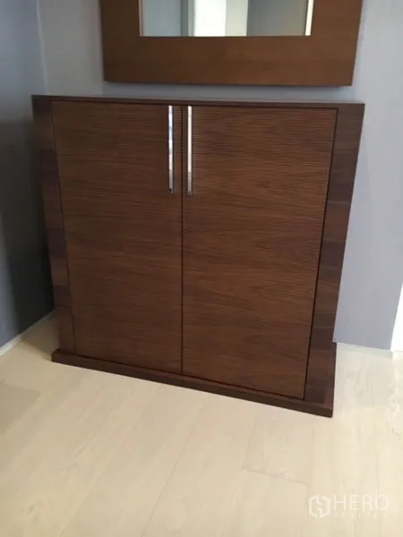 Detached House for rent in Wang Thonglang, Bangkok - Modern wooden cabinet with chrome handles below a wall mirror.