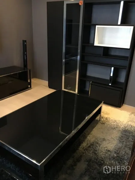 Detached House for rent in Wang Thonglang, Bangkok - Contemporary lounge space with a glossy black coffee table and built-in shelving unit.