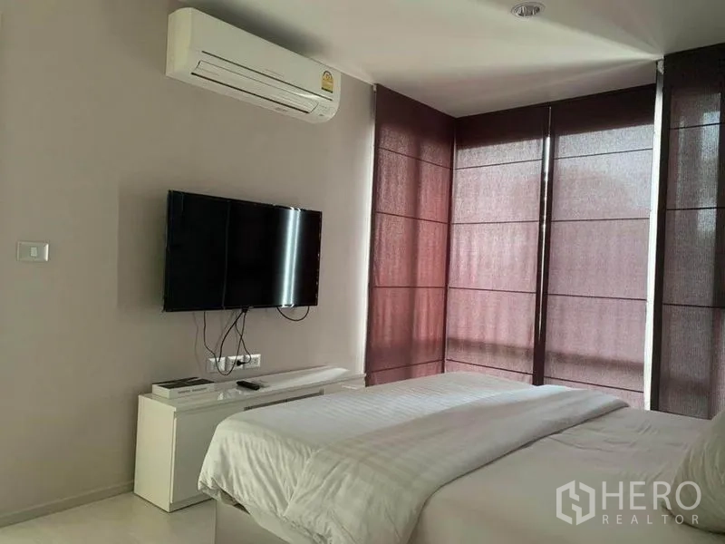 公寓 出租在Khlong Toei, Bangkok - 卧室一角，壁挂电视、空调与大窗搭配遮光帘