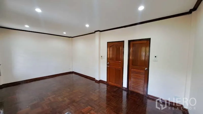 联排别墅 出租在Watthana, Bangkok - 宽敞房间，亮面木地板，两扇木门与筒灯