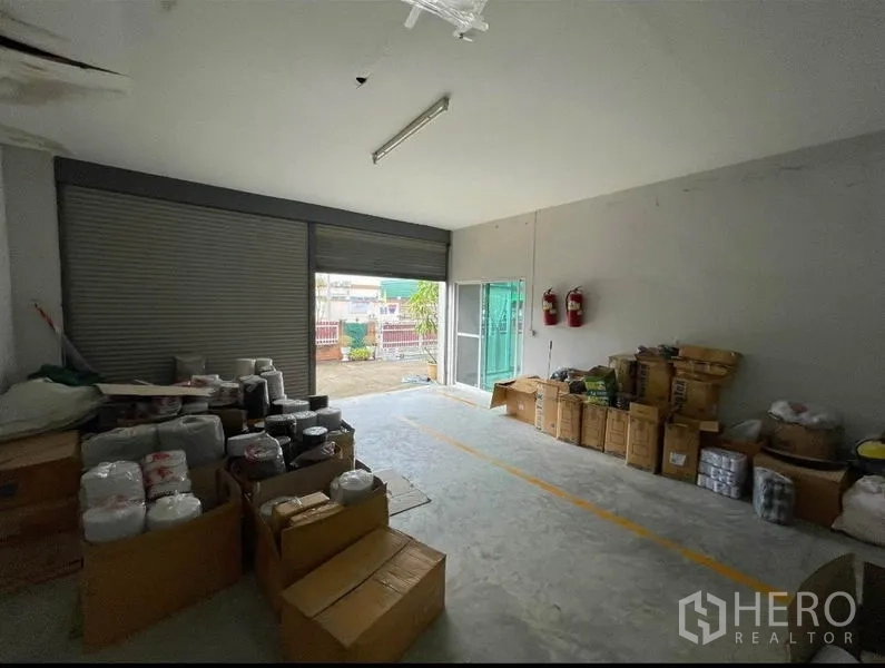 Warehouse for sale in Mueang Samut Sakhon, Samut Sakhon - Covered loading room with roller shutter door and stacked cartons ready for dispatch.