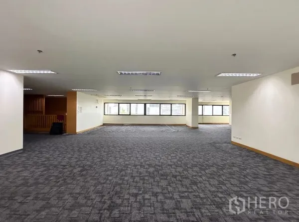 Office Space for rent in Bang Rak, Bangkok - Large open workspace with long window line and ceiling fluorescent lights.
